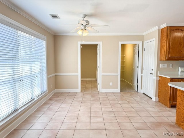 kitchen with light countertops, brown cabinetry, visible vents, and a wealth of natural light