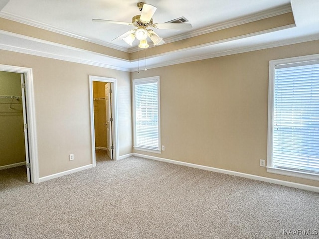 unfurnished bedroom featuring a spacious closet, visible vents, crown molding, carpet, and a raised ceiling