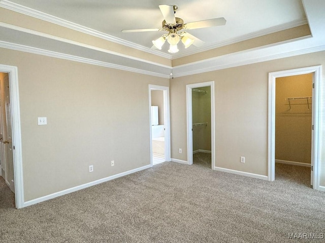 unfurnished bedroom featuring connected bathroom, a walk in closet, ornamental molding, carpet floors, and a closet