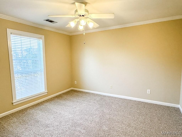 carpeted empty room featuring visible vents, baseboards, crown molding, and ceiling fan