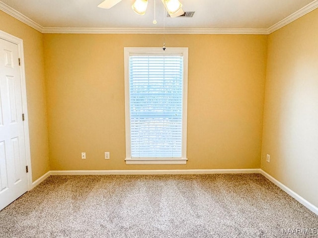 carpeted empty room featuring crown molding, a ceiling fan, visible vents, and baseboards