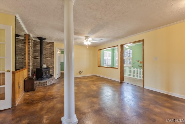 unfurnished living room with finished concrete flooring, baseboards, a wood stove, ceiling fan, and a textured ceiling