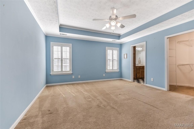 unfurnished bedroom with a tray ceiling, baseboards, a textured ceiling, and ornamental molding