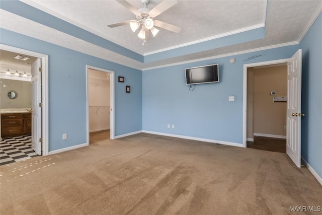 unfurnished bedroom with baseboards, crown molding, a tray ceiling, and carpet floors