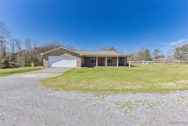 view of front facade featuring brick siding, gravel driveway, a front lawn, covered porch, and an attached garage