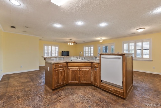 kitchen with visible vents, open floor plan, white dishwasher, brown cabinetry, and a sink