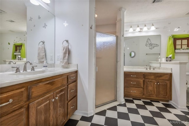 full bath with tile patterned floors, a stall shower, two vanities, and a sink