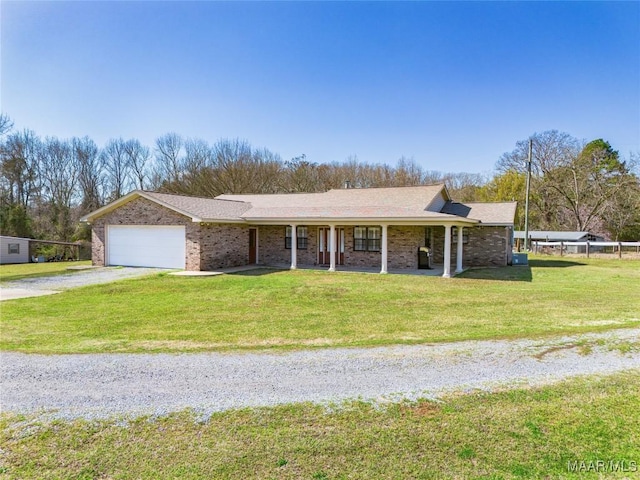 view of front facade with a front lawn, a porch, gravel driveway, an attached garage, and brick siding