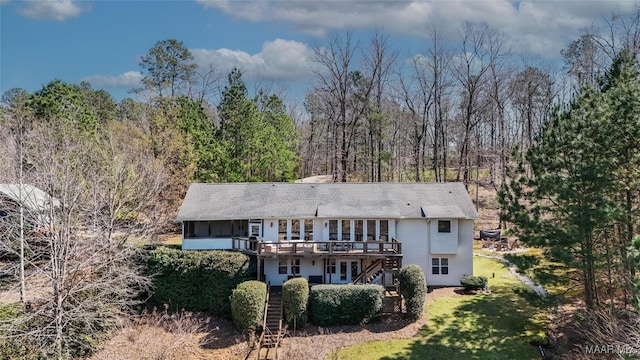 back of property featuring stairway, a forest view, a yard, and a deck