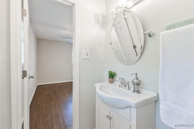 bathroom with vanity, wood finished floors, and baseboards