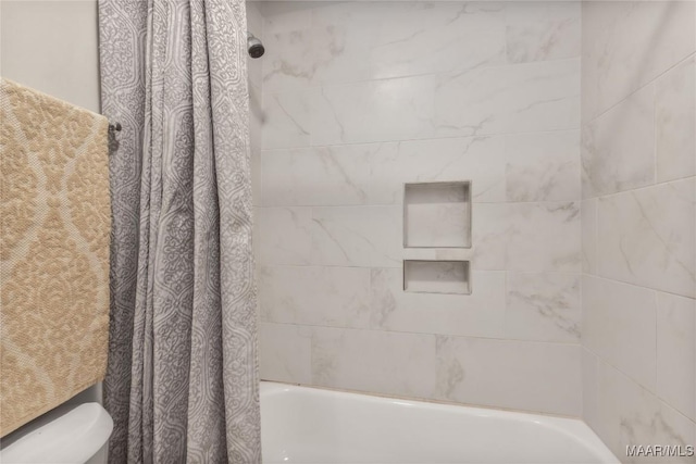 bathroom featuring shower / tub combo and toilet