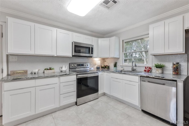 kitchen featuring light stone counters, visible vents, ornamental molding, white cabinets, and appliances with stainless steel finishes