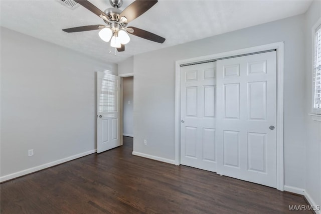 unfurnished bedroom featuring a closet, baseboards, dark wood-type flooring, and a ceiling fan