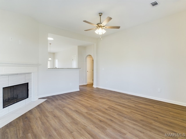 unfurnished living room featuring visible vents, a ceiling fan, wood finished floors, a fireplace, and baseboards