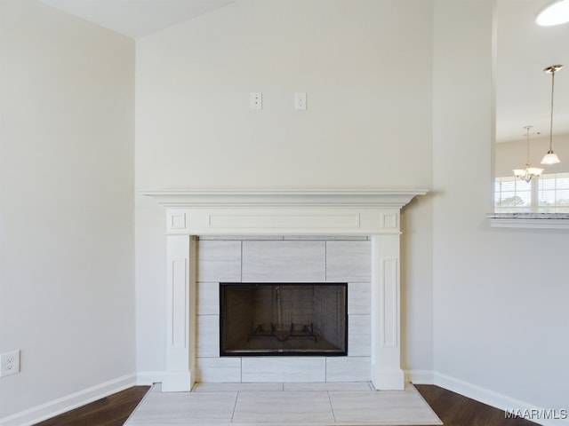 details featuring wood finished floors, baseboards, a chandelier, and a fireplace