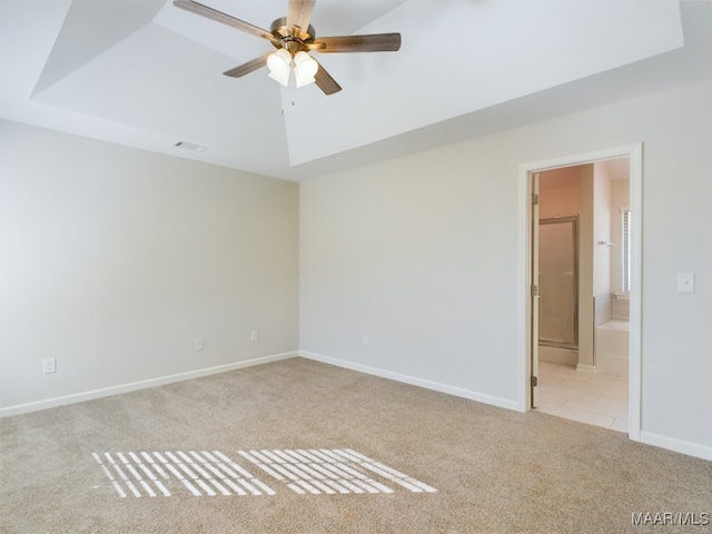 carpeted empty room featuring a raised ceiling, a ceiling fan, visible vents, and baseboards