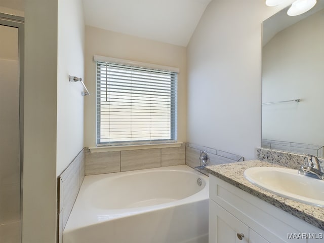 bathroom with a bath, vanity, and lofted ceiling