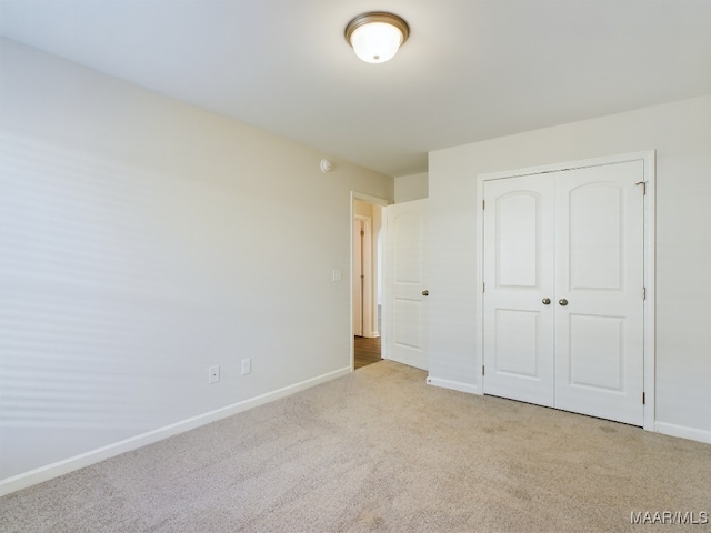 unfurnished bedroom with carpet, baseboards, and a closet