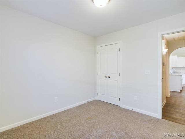 unfurnished bedroom with attic access, carpet flooring, baseboards, and a closet