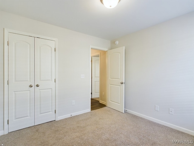 unfurnished bedroom featuring a closet, baseboards, and carpet