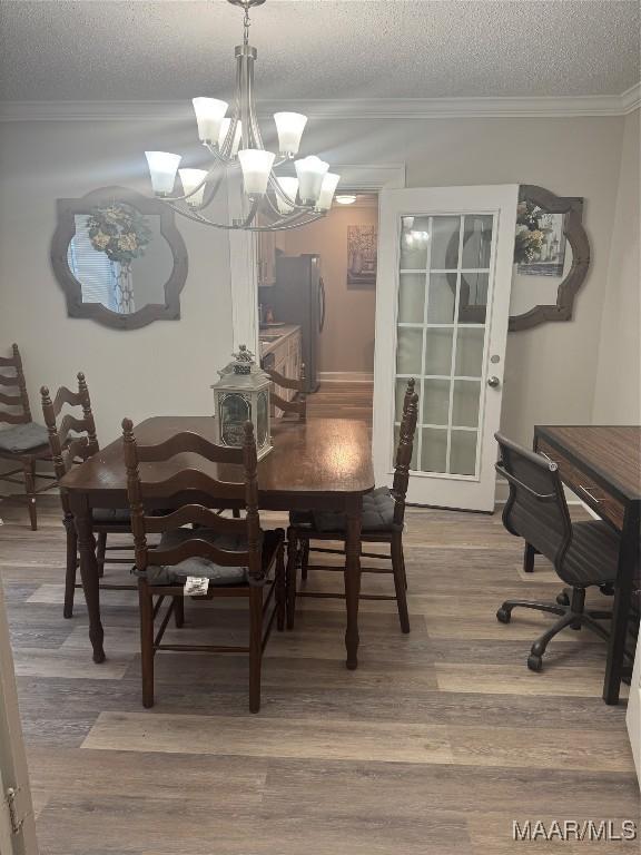 dining space featuring an inviting chandelier, wood finished floors, crown molding, and a textured ceiling