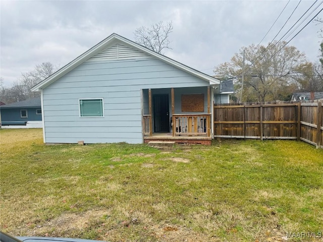 back of house featuring a lawn and fence