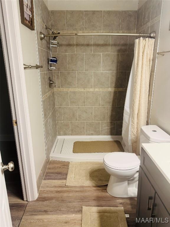 bathroom with vanity, a shower stall, toilet, and wood finished floors