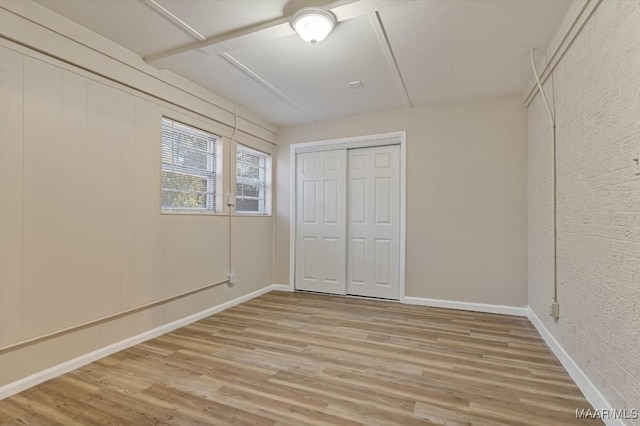 unfurnished bedroom with a closet, baseboards, and light wood-style floors