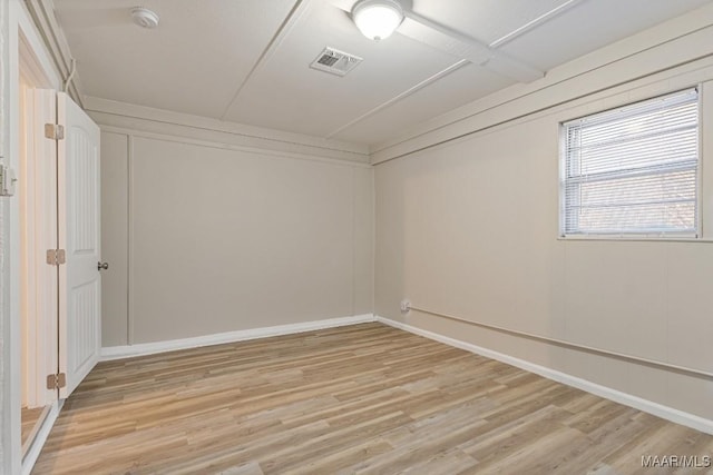 unfurnished room with light wood finished floors, visible vents, and baseboards