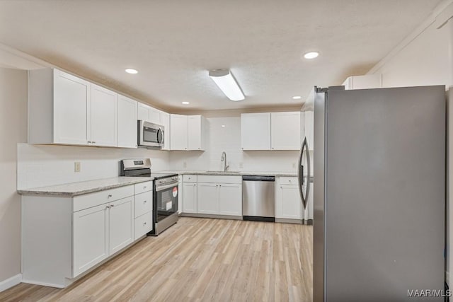 kitchen featuring a sink, white cabinets, light wood-style floors, and stainless steel appliances