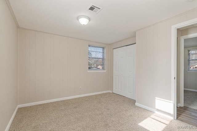 unfurnished bedroom with visible vents, baseboards, light colored carpet, and a closet