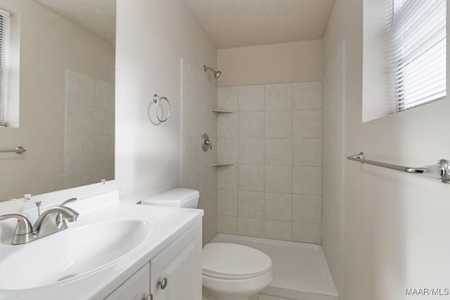 bathroom with tiled shower, a textured ceiling, toilet, and vanity