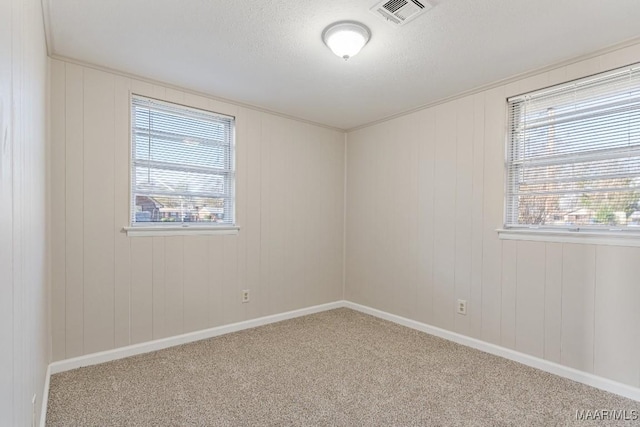 carpeted empty room with visible vents, baseboards, and a textured ceiling