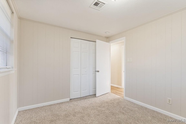 unfurnished bedroom with carpet, visible vents, a closet, and baseboards