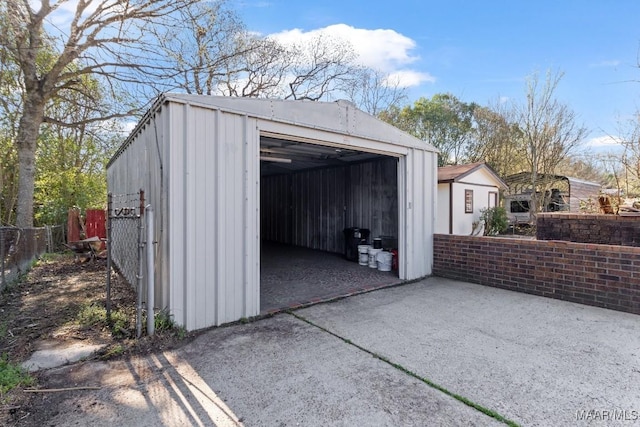 detached garage with concrete driveway and fence