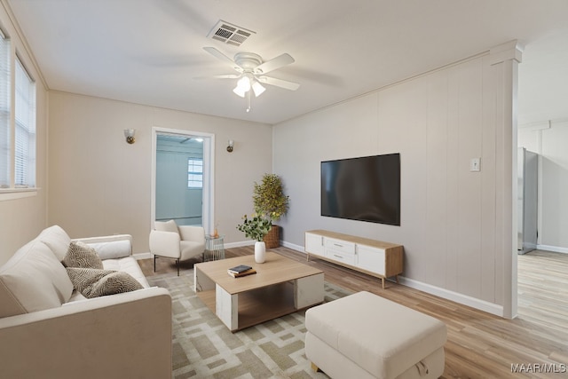 living room featuring visible vents, light wood-style flooring, baseboards, and a ceiling fan