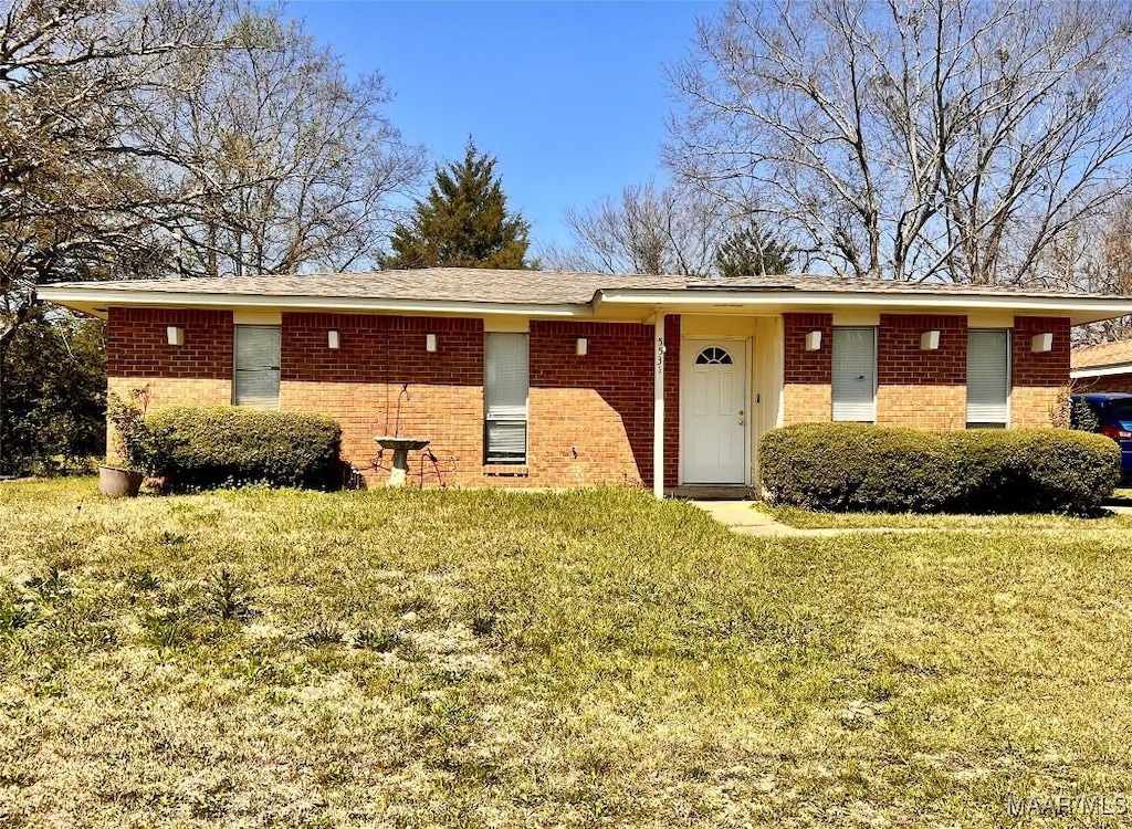 ranch-style home featuring brick siding and a front yard