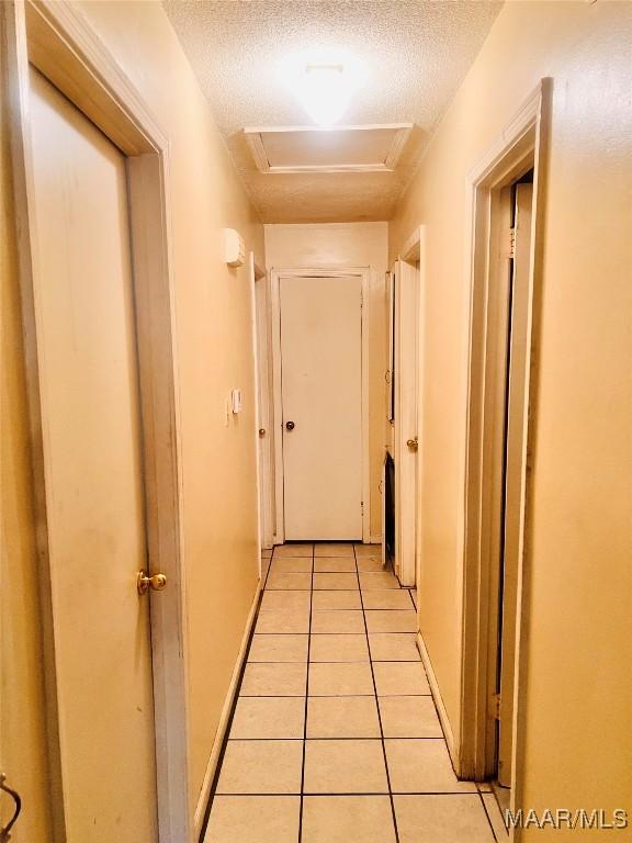 5531 E Shades Valley Dr, Montgomery, AL 36108 - corridor with attic access, light tile patterned flooring, and a textured ceiling
