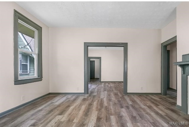 spare room featuring baseboards, a textured ceiling, and wood finished floors