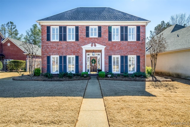 colonial-style house with brick siding and a front lawn