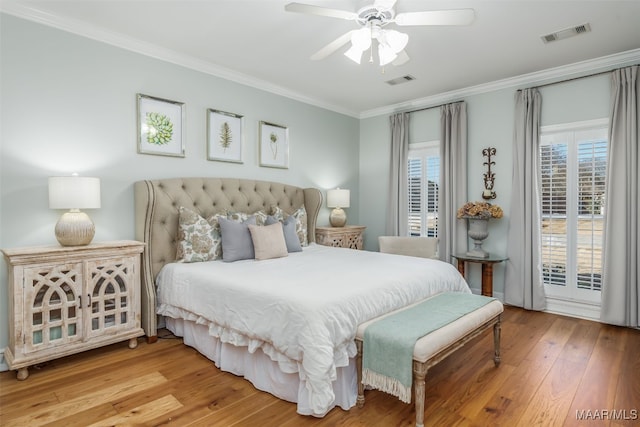 bedroom featuring visible vents, hardwood / wood-style floors, ceiling fan, and ornamental molding