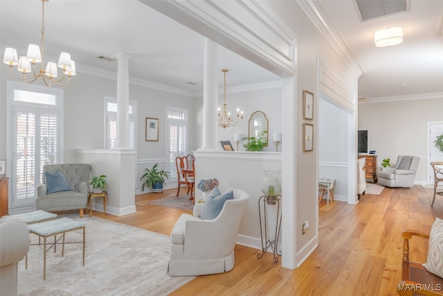 living area featuring wood finished floors, a healthy amount of sunlight, visible vents, and a chandelier