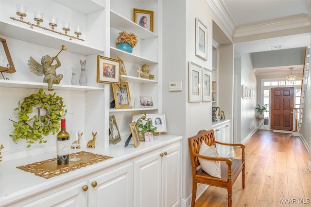 bar featuring crown molding, visible vents, and light wood finished floors