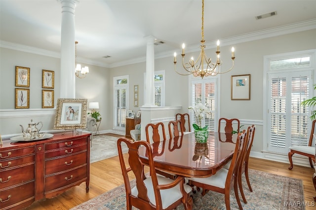 dining space featuring light wood finished floors, visible vents, ornamental molding, decorative columns, and an inviting chandelier