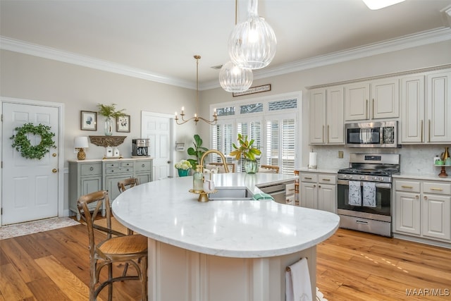 kitchen featuring a notable chandelier, light wood-style flooring, ornamental molding, a sink, and appliances with stainless steel finishes