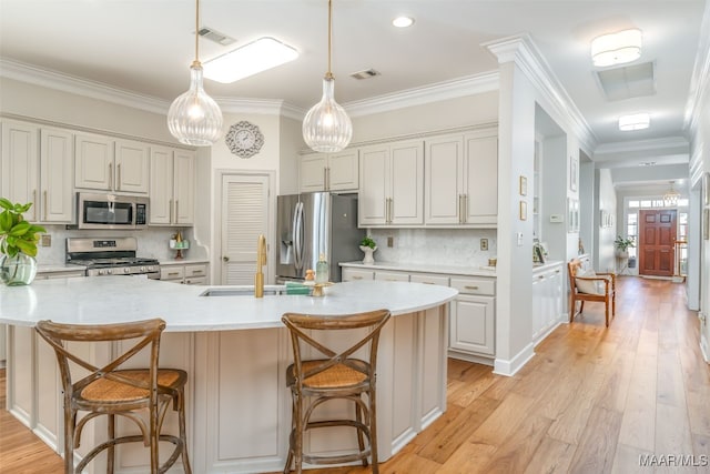 kitchen with visible vents, a sink, light wood-style floors, appliances with stainless steel finishes, and crown molding