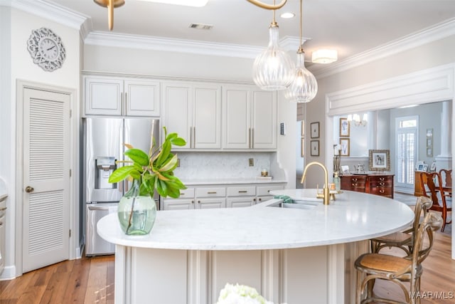 kitchen with a sink, visible vents, stainless steel fridge with ice dispenser, and crown molding