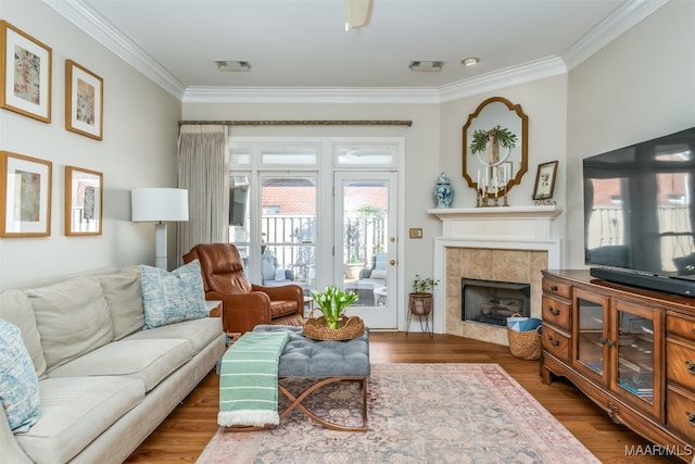 living area featuring crown molding, wood finished floors, and visible vents