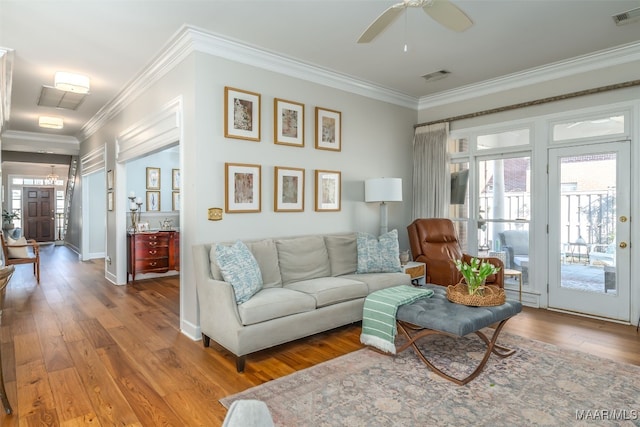 living room featuring a ceiling fan, wood finished floors, visible vents, and ornamental molding