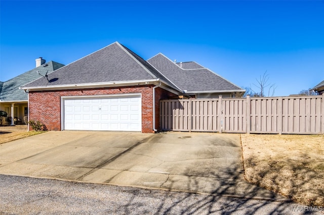 view of side of property featuring fence, concrete driveway, an attached garage, a shingled roof, and brick siding